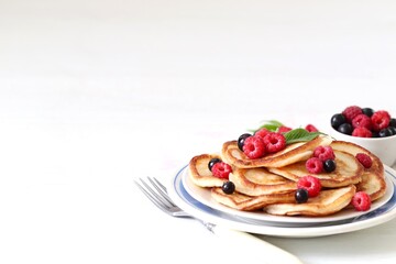 Pancakes with fresh raspberries and black currant on a plate on a white background copy space 