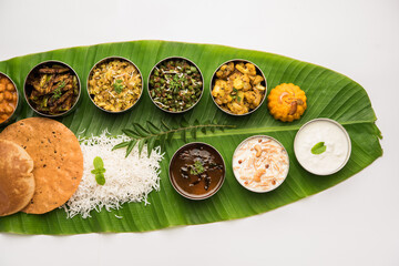 South Indian style lunch or dinner meal or food served with a selection of recipes over banana leaf