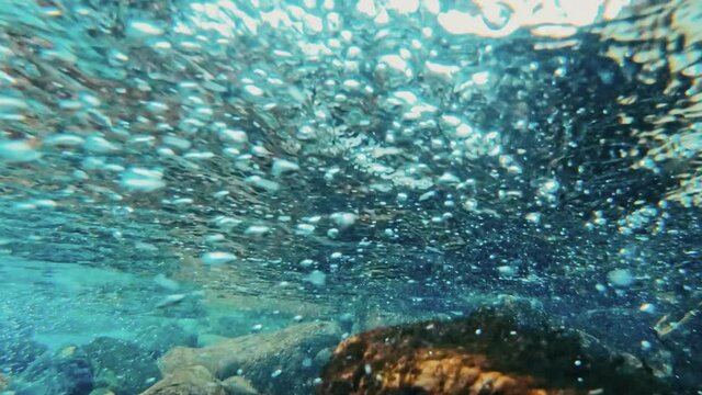 Mountain river with rocks, clear water and bubbles, underwater video shooting