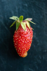 One raw strawberry on black background