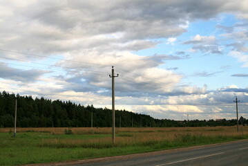 Fototapeta na wymiar landscape road to the field, forest and Cumulus clouds