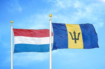 Netherlands and Barbados two flags on flagpoles and blue sky