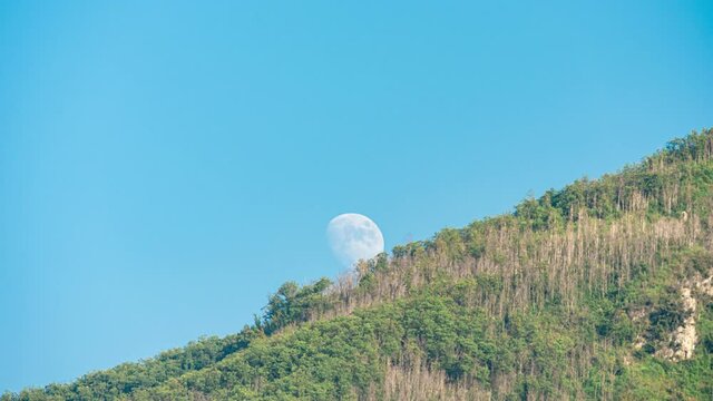 Angri, Italy. July 30th, 2020. Rising Waxing Gibbous Moon rises from behind the ridge of Mount Taccaro and continues along the line of the mountain ridge while remaining partly hidden at times.
