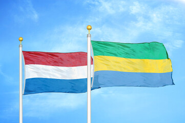 Netherlands and Gabon two flags on flagpoles and blue sky