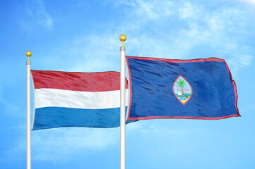 Netherlands and Guam two flags on flagpoles and blue sky