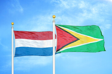Netherlands and Guyana two flags on flagpoles and blue sky