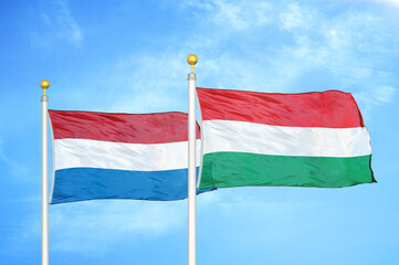 Netherlands and Hungary two flags on flagpoles and blue sky