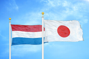 Fototapeta na wymiar Netherlands and Japan two flags on flagpoles and blue sky