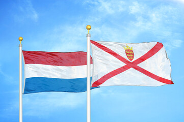Fototapeta premium Netherlands and Jersey two flags on flagpoles and blue sky
