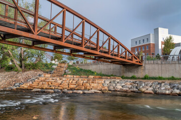 bike trail and footbridge - Cache la Poudre River at whitewater park in downtown of Fort Collins Colorado with Powerhouse Energy Campus of Colorado State University in background