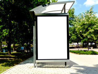 bus shelter. blank ad panel. billboard display. blank white lightbox poster sign at bus stop. digital glass panel. city transit station. urban street. green street setting. outdoor poster advertising