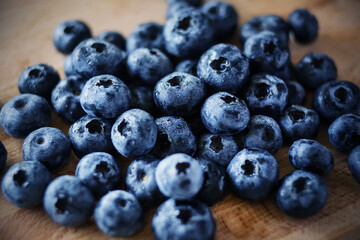 On a wooden kitchen board lie ripe delicious sweet blue berries of forest blueberries. Rich harvest.