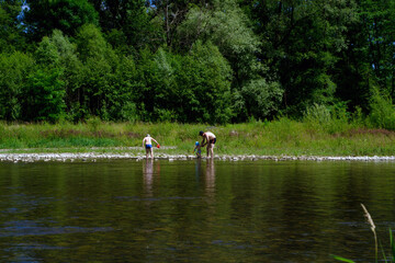 Fototapeta premium Bielsko Biala, Poland - July 04, 2020: A family consists of Father and two sons at the bay of Sola river near Wieprz