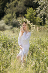 Fototapeta na wymiar Young white woman with blondy hair dressed in a white dress in summer in a field