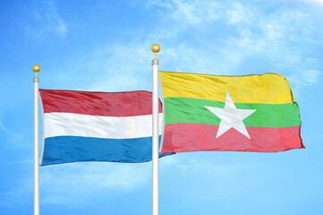 Netherlands and Myanmar two flags on flagpoles and blue sky