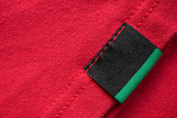 Black blank laundry care clothes label on red cotton shirt background