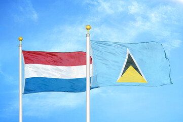 Netherlands and Saint Lucia two flags on flagpoles and blue sky