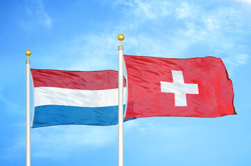 Netherlands and Switzerland two flags on flagpoles and blue sky