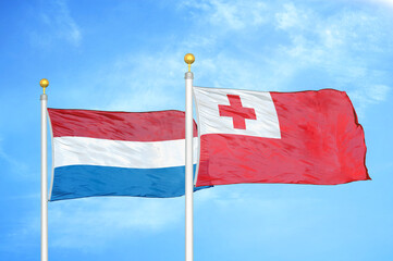 Netherlands and Tonga two flags on flagpoles and blue sky