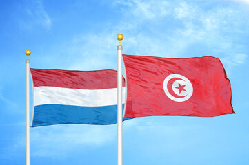 Netherlands and Tunisia two flags on flagpoles and blue sky