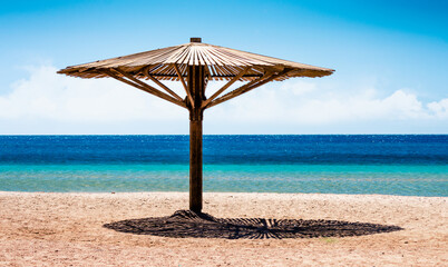 wooden beach umbrella on the shore without people of the Red Sea in Egypt