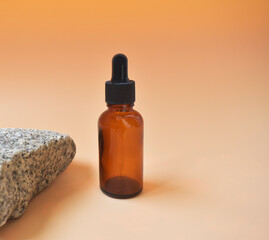 Cosmetic oil in a bottle with a pipette for the face and body on a natural background with a decor in the form of a natural stone. Space for text.