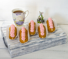Yummy vanilla eclairs on wood with flower decoration