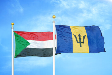 Sudan and Barbados two flags on flagpoles and blue sky