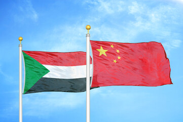Sudan and China two flags on flagpoles and blue sky