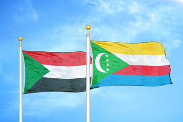 Sudan and Comoros two flags on flagpoles and blue sky