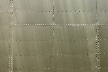 Details of the fuselage of an old aircraft. Old camouflage surface with exfoliated paint and rivets on a military aircraft.