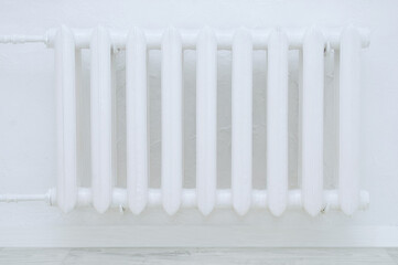 White metal retro radiator of water heating on  background of a white wall in the room.