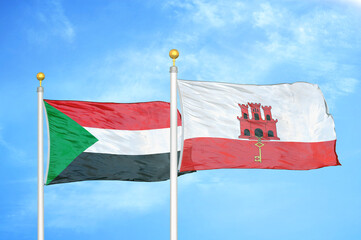 Sudan and Gibraltar two flags on flagpoles and blue sky