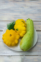 Harvest zucchini and mini patty pan squash on a wooden table close-up