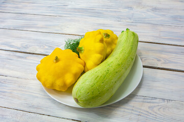 Green zucchini and yellow mini patty pan squashes on a wooden background. Autumn harvest vegetables