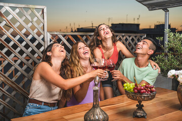 Happy Friends Laughing Loud and Toasting Red Wine Together with White and Red black Grapes on the Table. Balcony Concept with Friends that Spending their Time with Fun.