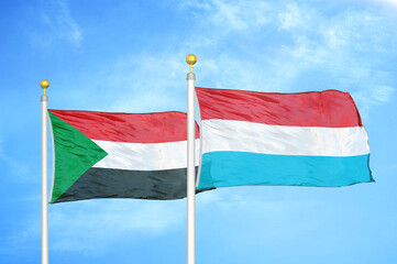 Sudan and Luxembourg two flags on flagpoles and blue sky