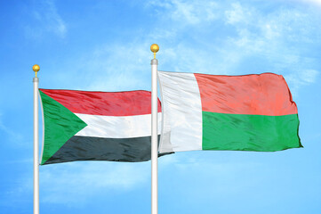 Sudan and Madagascar two flags on flagpoles and blue sky