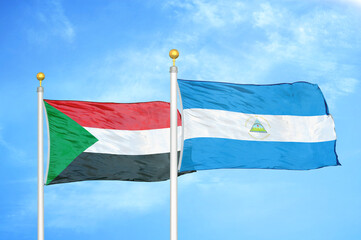 Sudan and Nicaragua two flags on flagpoles and blue sky