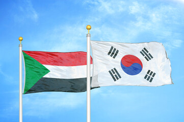 Sudan and South Korea two flags on flagpoles and blue sky