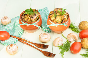 Baked potatoes with mushrooms and homemade meat in a clay pot. On a light green background.