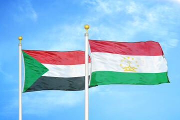 Sudan and Tajikistan two flags on flagpoles and blue sky