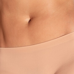 Close-up of young woman's body in skin color panties.
