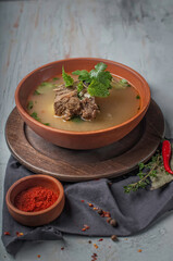 dietary meal, rich meat broth with piece of boiled beef, parsley and mint on gray textured background
