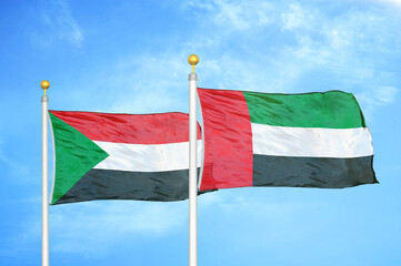 Sudan and United Arab Emirates two flags on flagpoles and blue sky