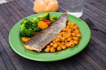 appetizing cooked trout, chickpeas, broccoli on green plate