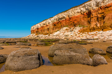 Barnacle encrusted rocks, rockfalls of varying colour and partially reflecting rock pools at the...