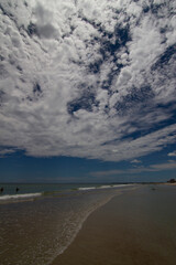 Beach scene with clouds rocks ocean and sun
