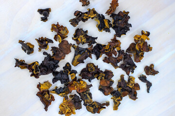 Dried black mushroom scatter on white kitchen table. Wood ear mushroom pile top view photo. Dry mushroom for soup or garnish ingredient. Natural healthy food from chinese market. Asian cuisine dish