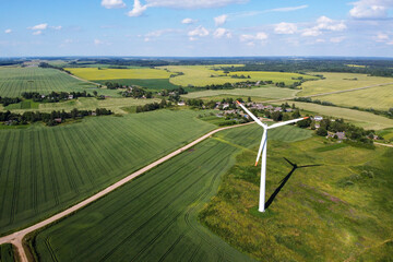 Aerial view of wind turbine and agricultural field, summer rural landscape. Wind power, sustainable and renewable energy